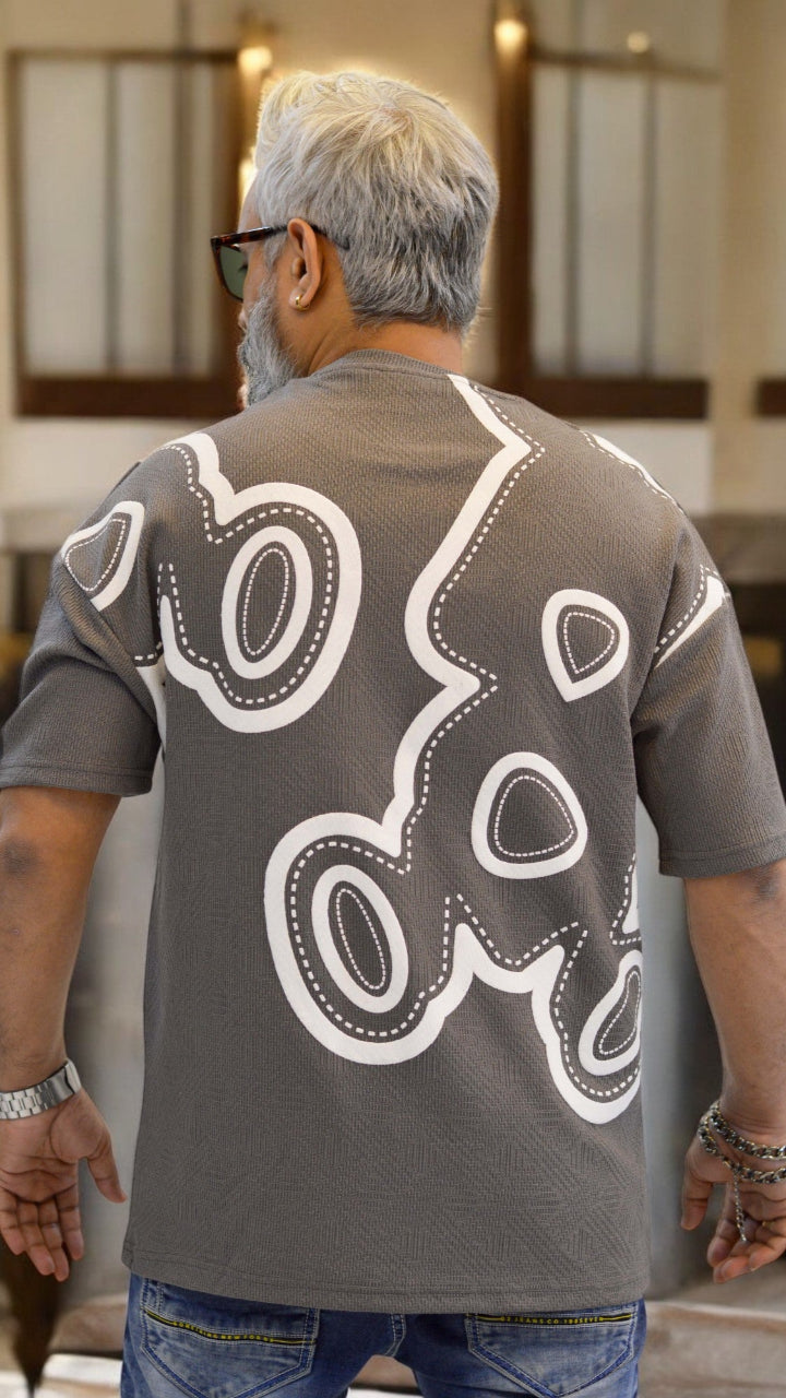 "Back view of grey oversized drop-shoulder T-shirt with bold puff print graphic"
